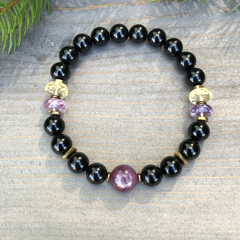 Black beaded bracelet with purple center gemstone, gold caps, and amethyst-colored accents