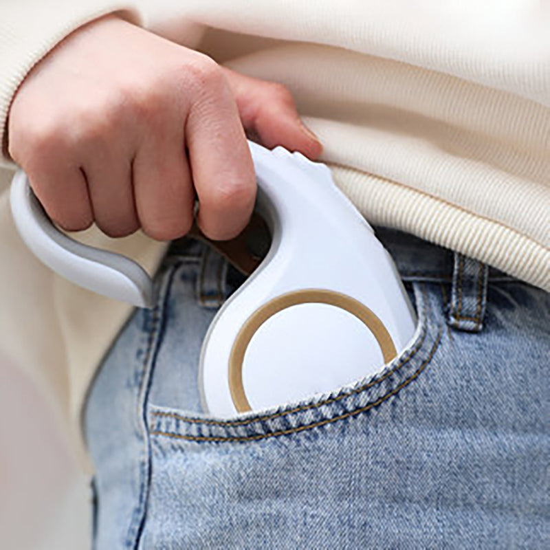 Automatic retractable dog leash held by hand over blue jeans, white casing with tan ring