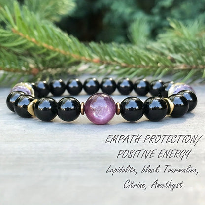Black beaded bracelet with round glossy beads and a purple center gemstone, gold accents
